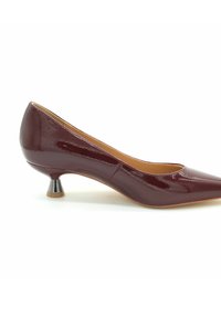 Décolleté in pelle patinata bordeaux con punta appuntita e tacca metallica bassa. Texture liscia con un design elegante e cuciture minime.