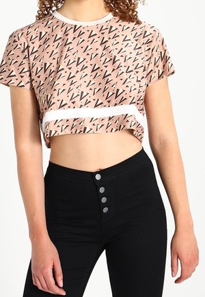 Camiseta corta rosa con un patrón geométrico negro, combinada con pantalones negros de cintura alta que presentan cinco botones en la parte frontal.