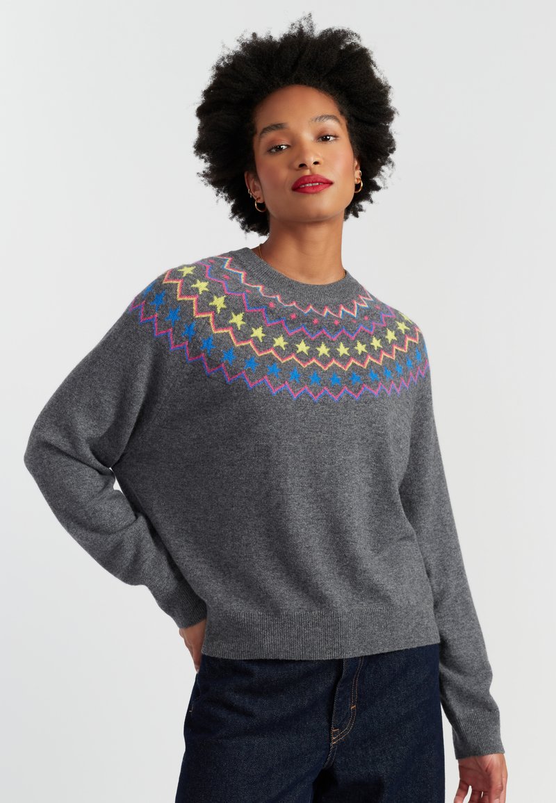 Pull en maille grise avec un col rond et un empiècement à motif étoile coloré en rose, jaune, bleu et vert. Texture douce et coupe décontractée.