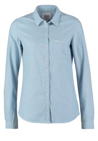 Ljusblå knapp-up skjorta med långa ärmar, i bomull, krage, en bröstficka och rundad nederkant. Har knapplist fram.
