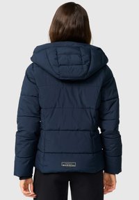 Marineblauwe pufferjack met capuchon, voorzien van horizontaal gestikte secties, zijzakken en een merlabel op de achterkant.