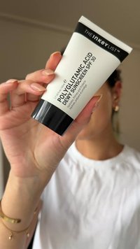 Tubetto di crema solare con corpo bianco e tappo nero, etichettato "POLIGLUTAMMICO ACIDO CREMA SOLARE IDRATANTE SPF 30", che mostra una consistenza liscia.