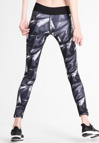 Leggings neri e grigi con un motivo geometrico, dotati di una vita alta e di una texture morbida e elastica. Adatti per abbigliamento sportivo.