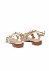 Sandali metallici dorati con tacco in legno, caratterizzati da decorazioni e un design a strisce per una vestibilità sicura.