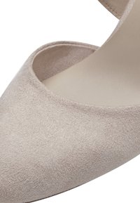 Chaussure à talon haut en daim beige avec une ouverture au niveau des orteils et une semelle intérieure lisse, présentée en gros plan.