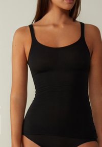 Top sin mangas negro hecho de tela suave, con tirantes finos y un diseño ajustado. El material tiene una textura suave y costuras mínimas.