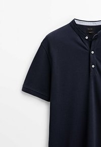 Polo bleu marine à manches courtes avec un col bandé et trois boutons blancs, présenté sur fond blanc.