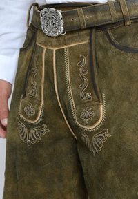 Bruine suède lederhosen met decoratieve geborduurde patronen, contrasterende beige stiksels en een zilveren decoratieve gesp op een leren riem.