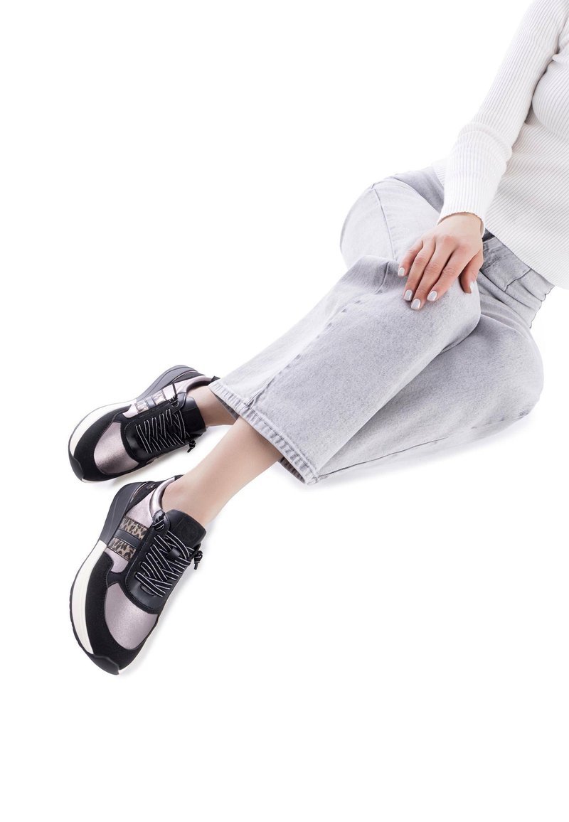 Zapatillas deportivas en negro y gris con una parte superior texturizada, puntera redonda y cordones. Tienen una suela gruesa y un patrón distintivo en los laterales.