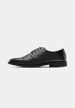 Black leather dress shoe with a rounded toe, lace-up design, subtle stitching details, and a low heel. Smooth texture with polished finish.