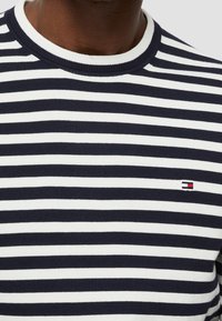 Marinblå och vit randig tröja med ribbad rundad hals och liten logotyp på vänster sida, tillverkad av stickad bomull.