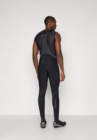 Mallas de ciclismo para hombre en negro, con parte superior de malla y piernas ajustadas. Acabadas con tejido texturizado y una marca visible en la pierna.