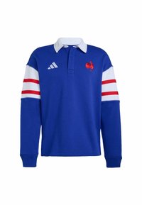 Maglia da rugby a maniche lunghe blu con colletto bianco, logo del gallo rosso e strisce rosse e bianche sulle maniche. Realizzata in tessuto misto cotone.