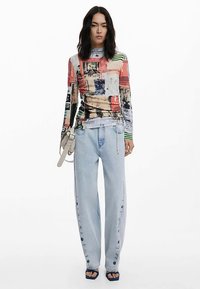 Hosszú ujjú, több színű felső absztrakt mintákkal; világoskék, széles szárú farmer gombos díszítéssel az oldalakon; fekete szandálok.