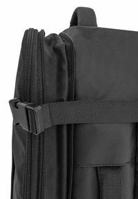 Czarna plecak z bliska, z teksturowanego nylonu, podwójnymi zamkami błyskawicznymi i solidnym zapięciem w postaci klamry, zapewniającym bezpieczne zamknięcie.