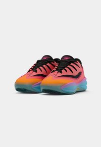 Une paire de baskets basses en orange, rose, noir et bleu avec des semelles à motifs et un laçage, sur fond blanc.