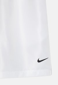 White athletic shorts made of smooth fabric. Features a black Nike swoosh logo at the lower right. Hem is neatly stitched.