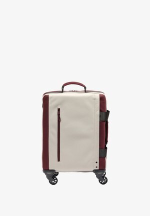 Kompaktowa beżowo-bordowa walizka z górnym uchwytem, przednią kieszenią na zamek, bocznymi paskami oraz czterema czarnymi kółkami obrotowymi, co zapewnia łatwość w poruszaniu się.