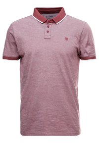 Polo shirt di un leggero color marrone scuro con colletto e bordi delle maniche di un marrone scuro a contrasto. Presenta una chiusura con tre bottoni e un tessuto leggermente testurizzato.