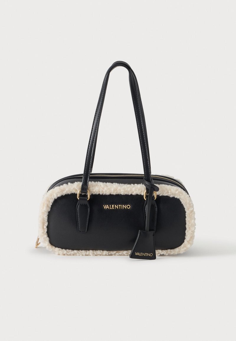 Μαύρη τσάντα Valentino με λευκή διακόσμηση από δέρμα προβάτου, δύο μακριά χερούλια, χρυσά γράμματα λογότυπου και ταιριαστή μαύρη ετικέτα, τοποθετημένη σε απλό φόντο.