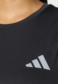 Μαύρο βαμβακερό t-shirt με απαλό υφαντό ύφασμα, που διαθέτει ασημένιο λογότυπο με τρεις διαγώνιες ρίγες στην αριστερή πλευρά. Στρογγυλή λαιμόκοψη.