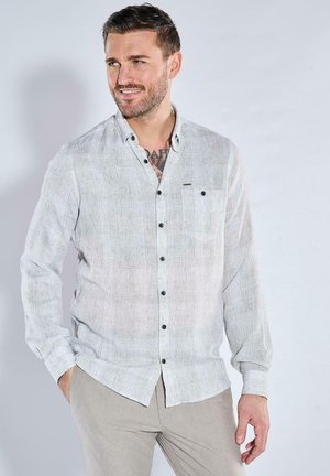 Helles graues Langarm-Hemd mit Knöpfen aus strukturiertem Stoff, ausgestattet mit einer Brusttasche und dunklen Knöpfen im lässigen Design.