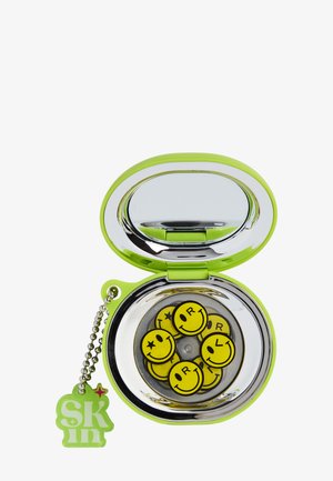 Espejo compacto verde con llavero adjunto y múltiples pines de caritas amarillas con sonrisa en el interior, cada uno con diferentes diseños de ojos y letras.