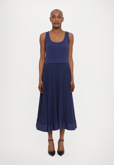 Navy blue sleeveless dress with a fitted top and pleated skirt. Features a round neckline and a flared hemline. Smooth fabric texture.