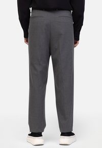 Grijze op maat gemaakte broek met een recht model, voorzien van twee achterzakken en een gladde textuur, gecombineerd met witte sneakers.