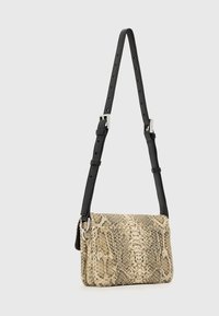 Borsa a tracolla con un esterno in ecopelle a trama effetto pitone in beige e nero. Presenta una tracolla nera regolabile e dettagli in metallo color argento.