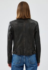 Giacca di pelle nera con design aderente, caratterizzata da spalline trapuntate, vita regolabile con cintura e polsini con zip. Vista posteriore mostrata.