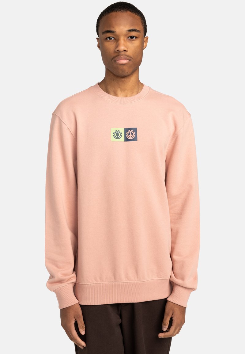 Light pink sweatshirt with ribbed cuffs, round neckline, and a central logo in green and navy on a block background. Soft texture, casual design.