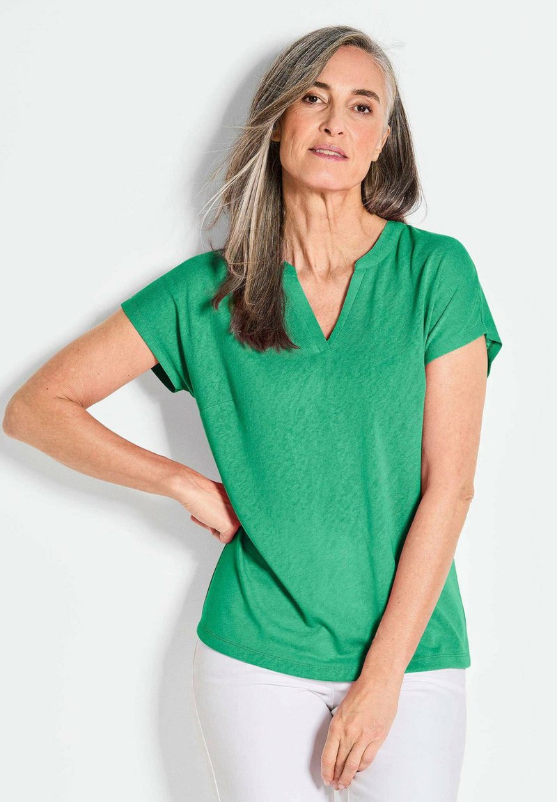 Groen kortearmpjes V-hals top gemaakt van lichtgewicht stof, met een ontspannen pasvorm en een klein borstzakje. Gladde textuur en effen kleur.