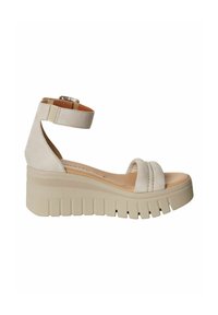 Sandali con zeppa in suede beige, dotati di due larghe cinghie e una cinghia alla caviglia regolabile. Presentano una suola in gomma spessa e rigata per un'altezza aggiuntiva.