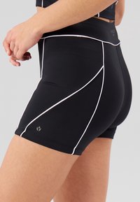 Černé sportovní šortky s bílým lemováním, přiléhavý střih, vysoký pas a detail loga u lemu. Vyrobené z pružné látky pro volnost pohybu.