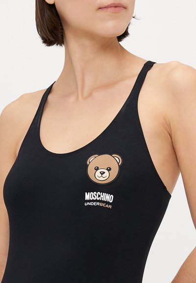 Melna bez piedurknēm peldkostīms ar lāča grafiku un balto uzrakstu "MOSCHINO UNDERBEAR". Gluda auduma struktūra ar pieguļošu dizainu.
