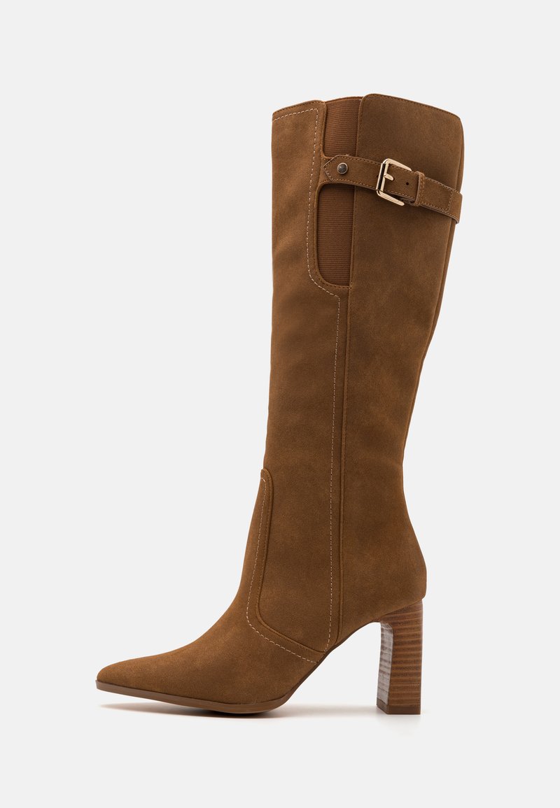 Bota alta de ante marrón con puntera afilada, tacón apilado, hebilla decorativa y panel elástico lateral para mayor flexibilidad.