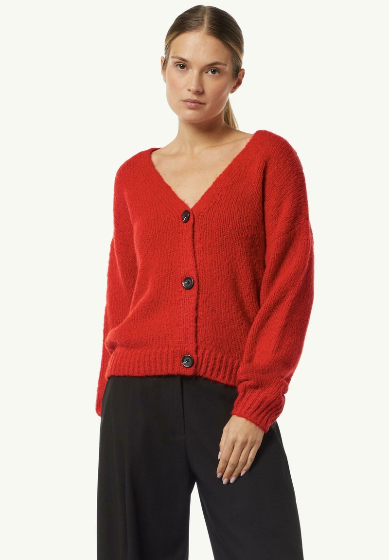 Roter gestrickter Cardigan mit tiefem V-Ausschnitt, langen Ärmeln und schwarzen Knöpfen, der eine strukturierte Oberfläche und einen gerippten Saum aufweist.