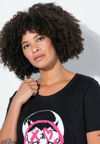 Camiseta negra con un diseño gráfico de calavera con acentos en rosa. Mangas cortas y un corte holgado, fabricada con una tela suave y texturizada.