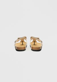 Smėlio spalvos basutės su atvira nugarėle, kamštine vidpadžio dalimi ir juodu guminio pado pagrindu. Turi reguliuojamas dirželius geresniam prigludimui ir patogumui.