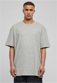 Grå bomull t-skjorte med klassisk rund hals, oversized passform, korte ermer og en subtil tekstur, kombinert med mørke denimbukser.