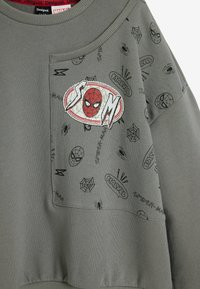 Tmavo šedý mikina s grafickým prvkom Spidermana a rôznymi malými čiernymi ilustráciami, vrátane pavúkov a log, vyrobená z mäkkej bavlny.