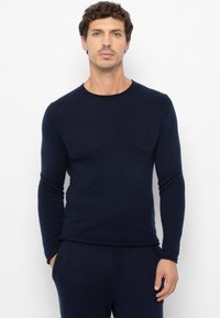 Marineblauem Pullover mit langen Ärmeln und rundem Ausschnitt, gefertigt aus einem weichen Strickmaterial. Schmale Passform mit einer glatten Textur.