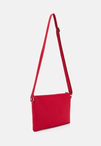 Borsa a tracolla rossa realizzata in tessuto morbido con chiusura a zip, a forma rettangolare slim e tracolla regolabile. Design semplice, senza motivi visibili.