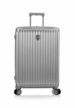 Valise rigide argentée avec des rainures verticales, quatre roues, poignée rétractable et emblème central sur le panneau avant.