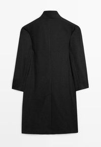 Cappotto nero con collo alto, maniche lunghe e silhouette dritta. Realizzato in tessuto strutturato con dettagli minimali e senza chiusure visibili.