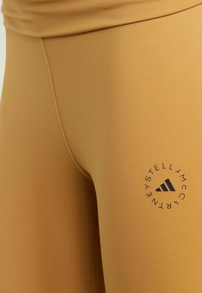 Bruine leggings van rekbaar materiaal met een gladde textuur. Voorzien van een ronde zwarte logo nabij de tailleband.