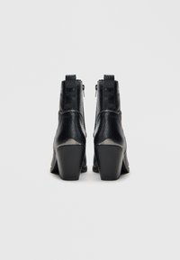 Botine negre cu toc, din piele texturată cu model de șarpe, cu închidere prin fermoar și toc conic pentru stabilitate și confort.