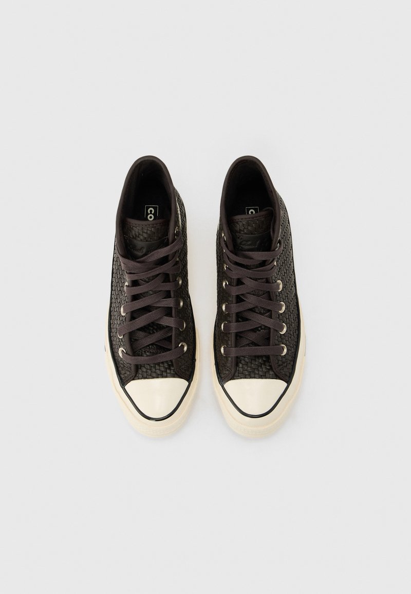 Black woven high-top sneakers with white rubber toe caps and black laces, viewed from above on a light background.