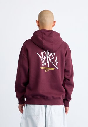 Sweatshirt à capuche bordeaux en mélange de coton doux. Présente un texte style graffiti blanc au dos et une poche kangourou à l'avant.